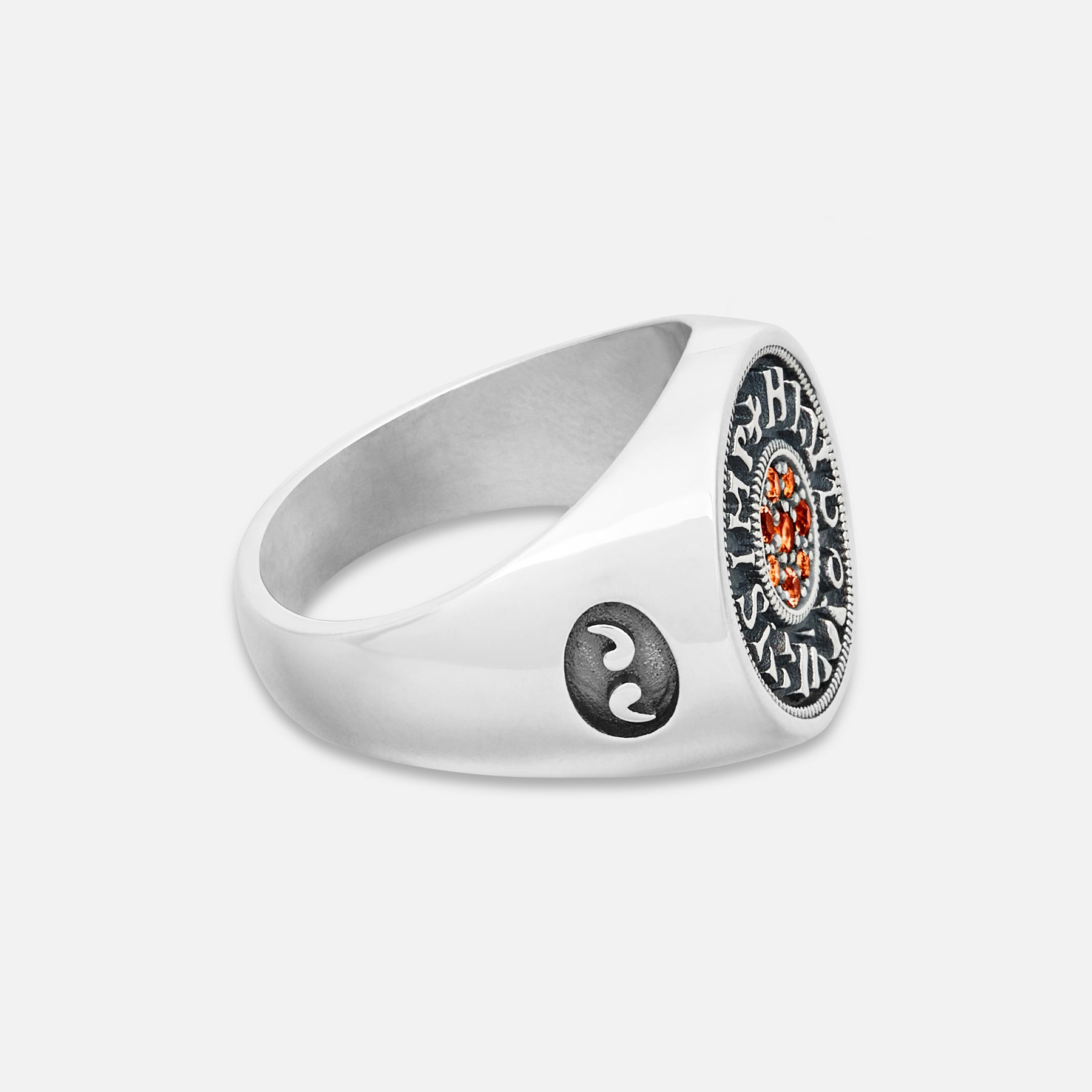 Silver ring with a yin yang symbol and red gemstone on a white background