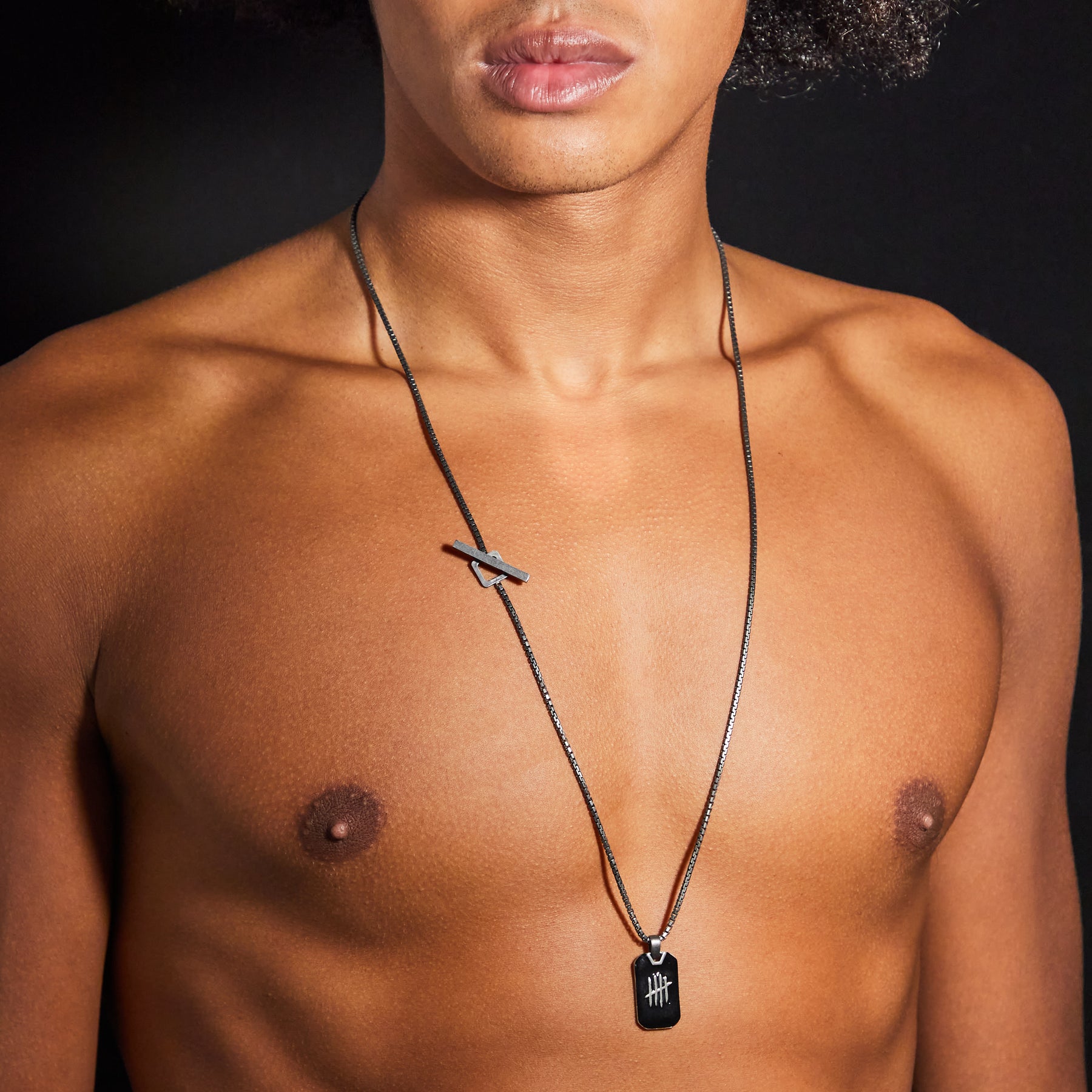 Man wearing a necklace with a pendant on a black background