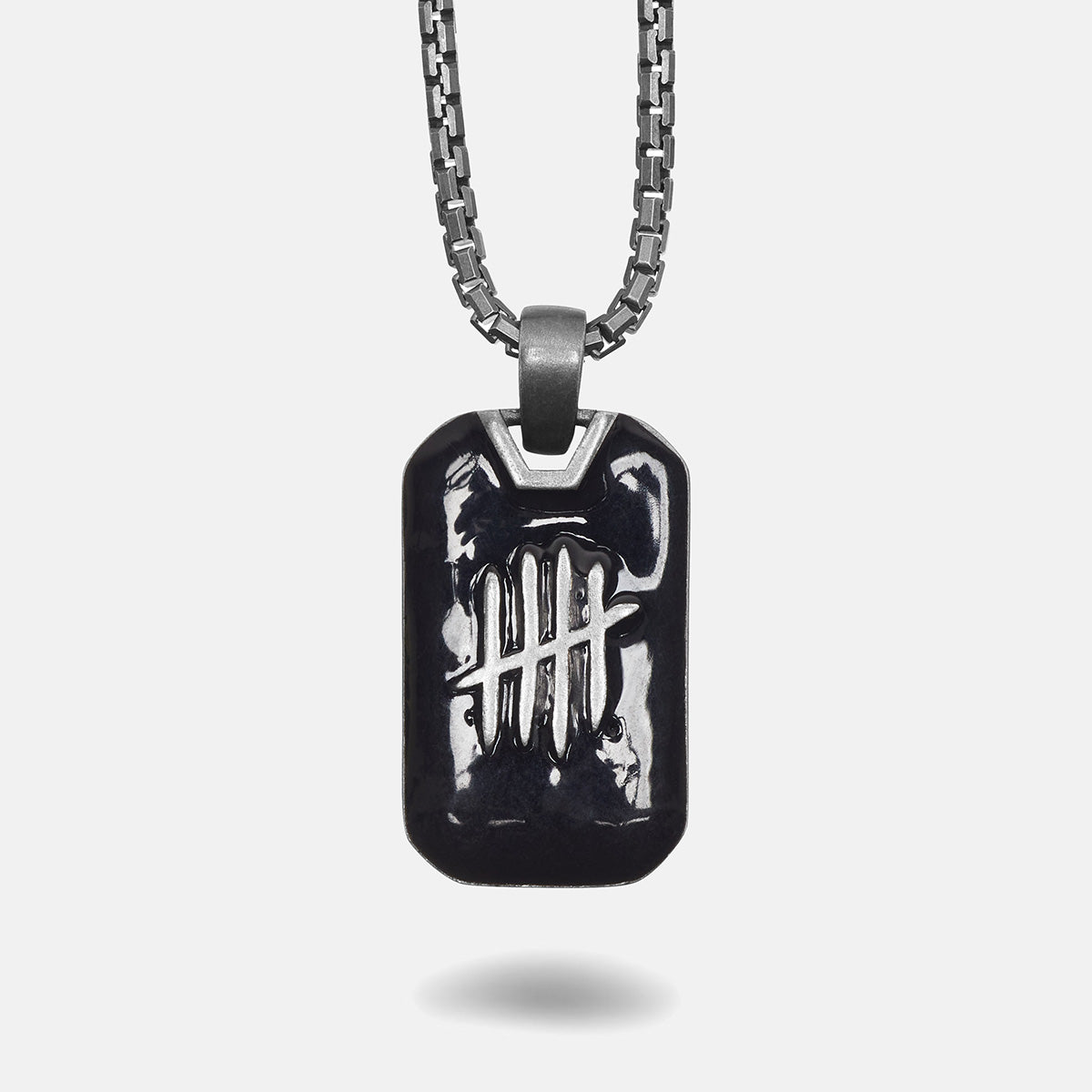 Black dog tag pendant on a chain against a white background