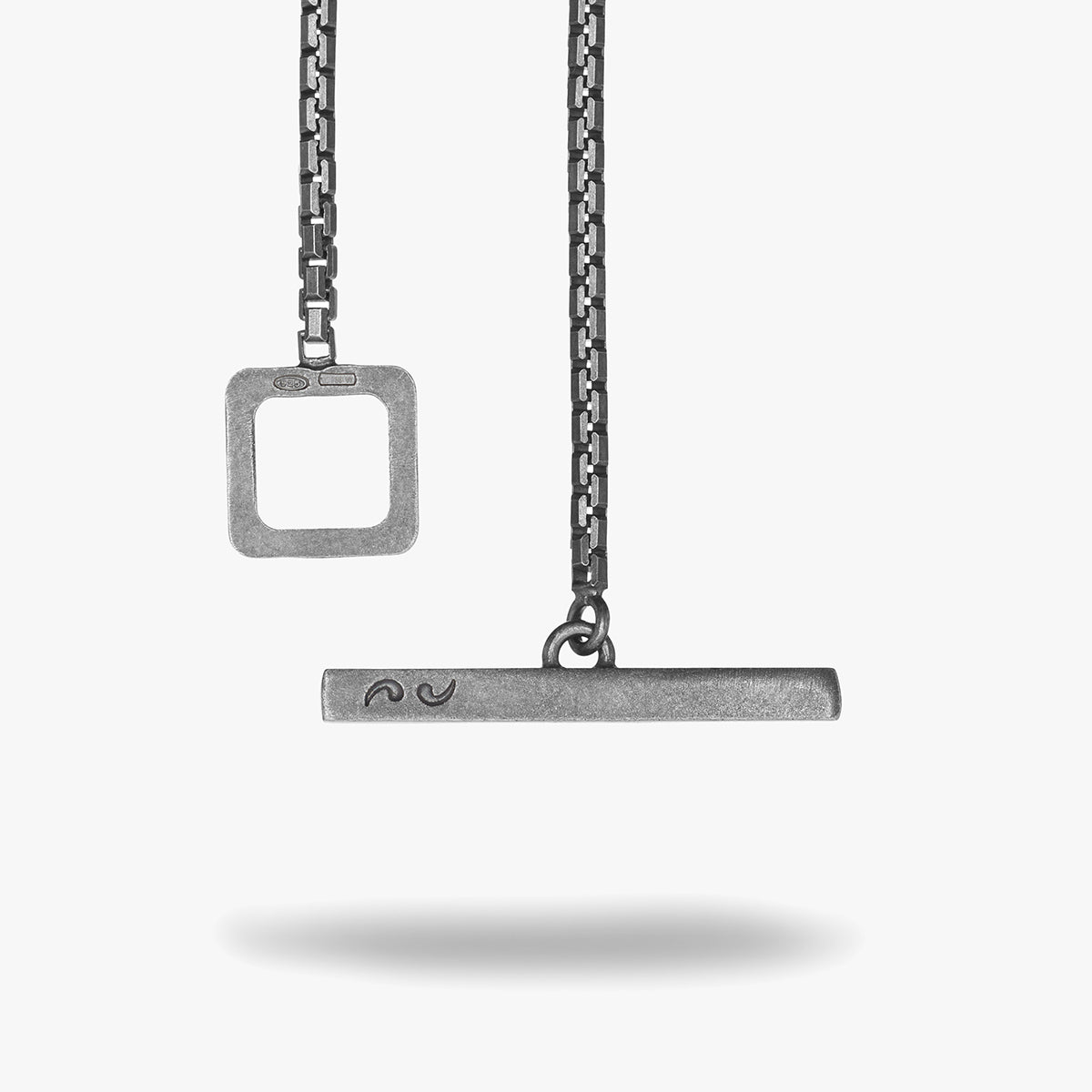 Two silver pendants on a chain against a white background