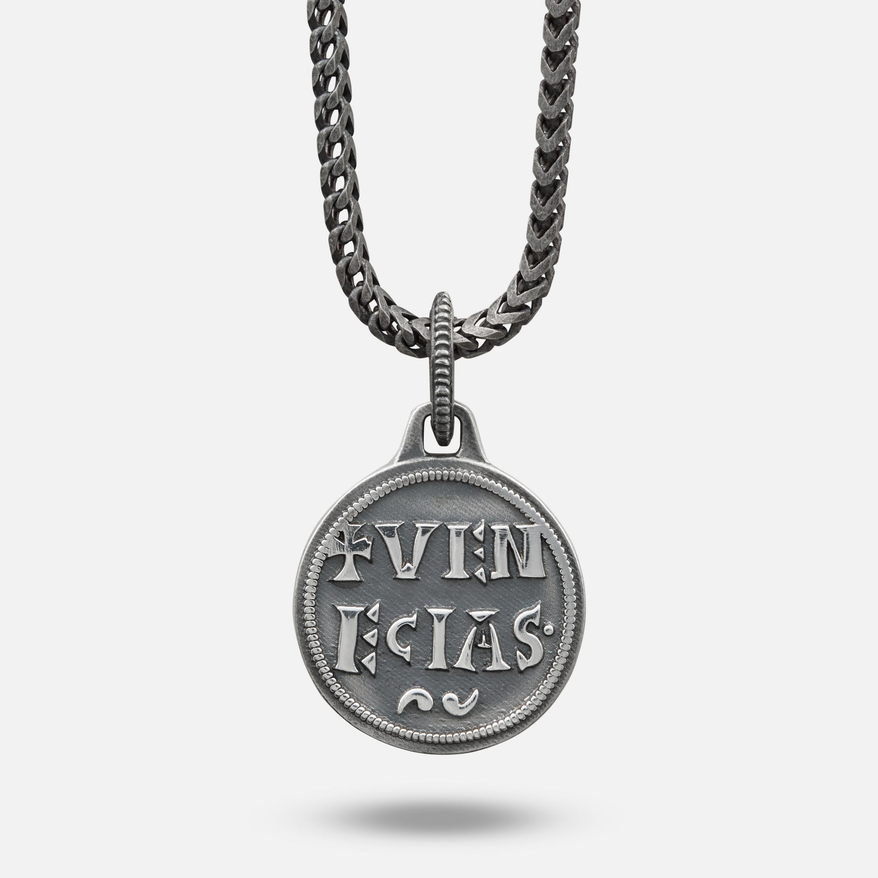 Silver pendant necklace with engraved text on a white background