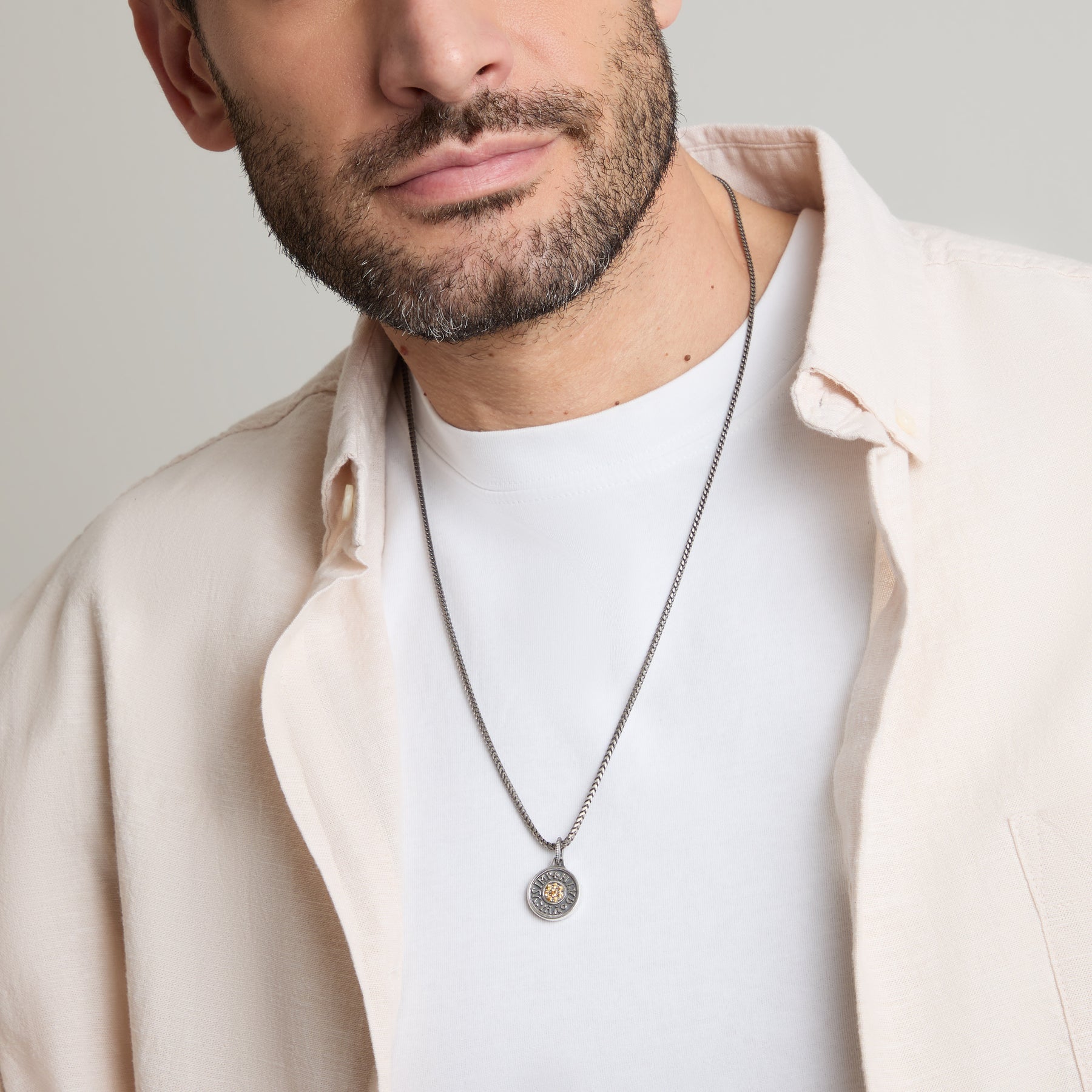Man wearing a necklace with a plain background