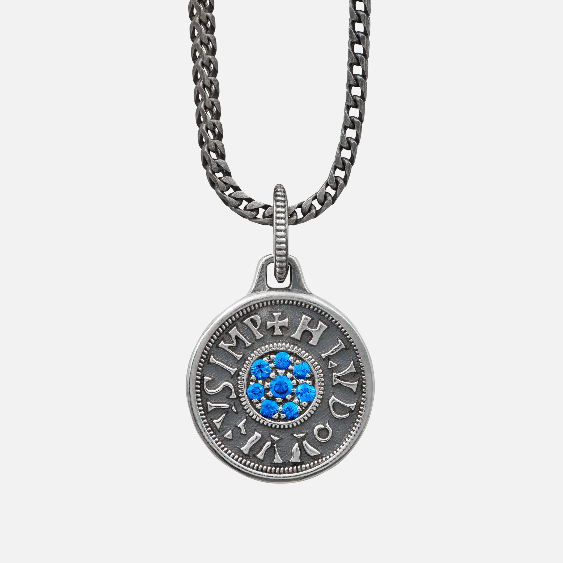 Silver necklace with a round pendant featuring blue stones on a light gray background