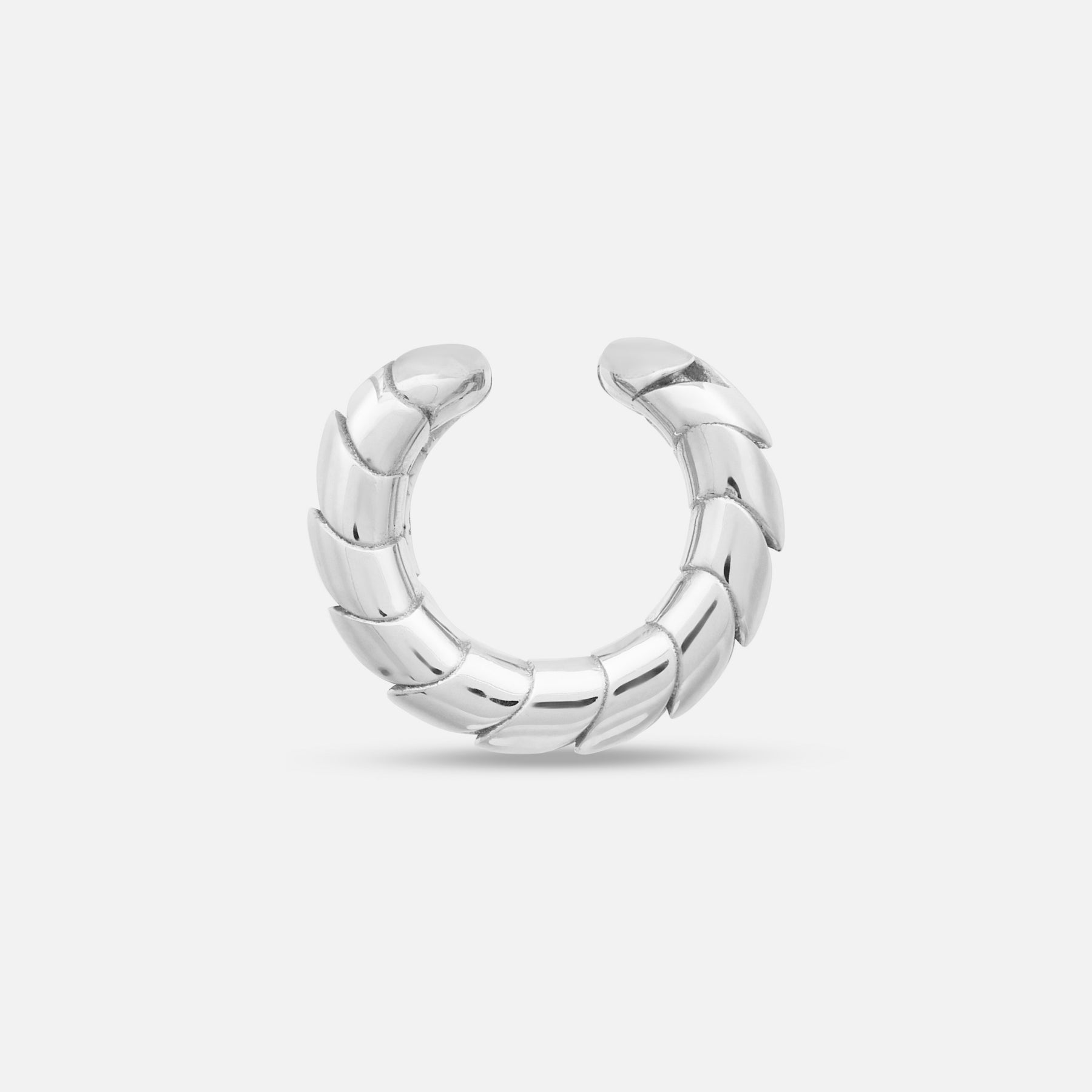 Side view of polished silver Iron Snake ear cuff on display.