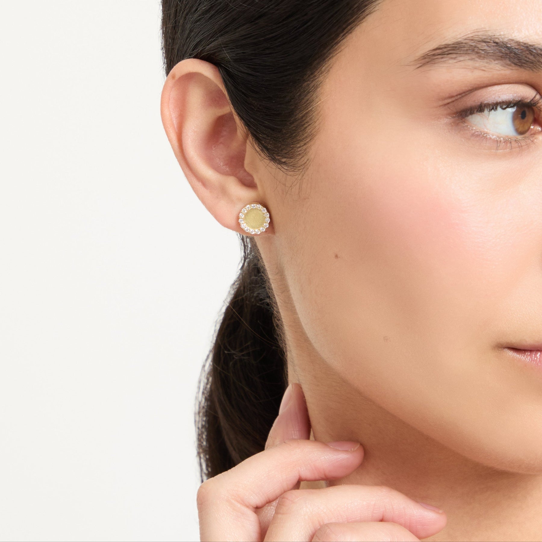 Close-up angle model wearing the Frammenti Halo Stud Earrings, featuring 18K matte gold and hand-set white diamonds.