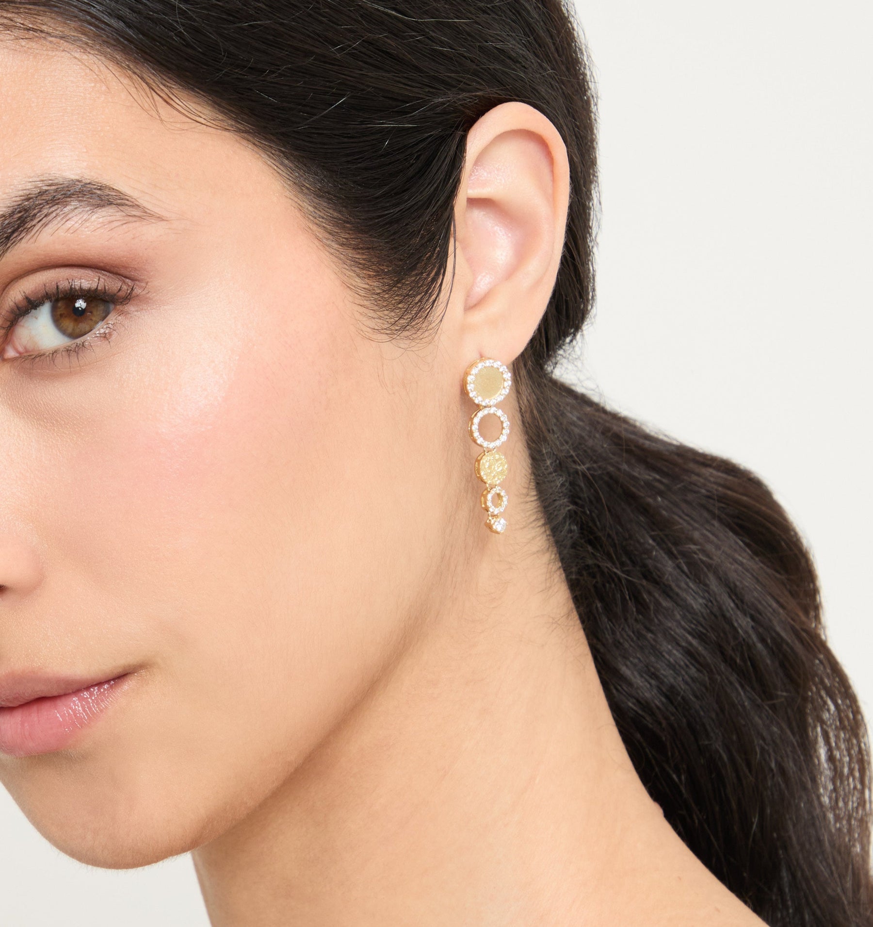 Close-up angle model wearing the Frammenti Cascade Earrings, featuring 18K matte gold and hand-set white diamonds.