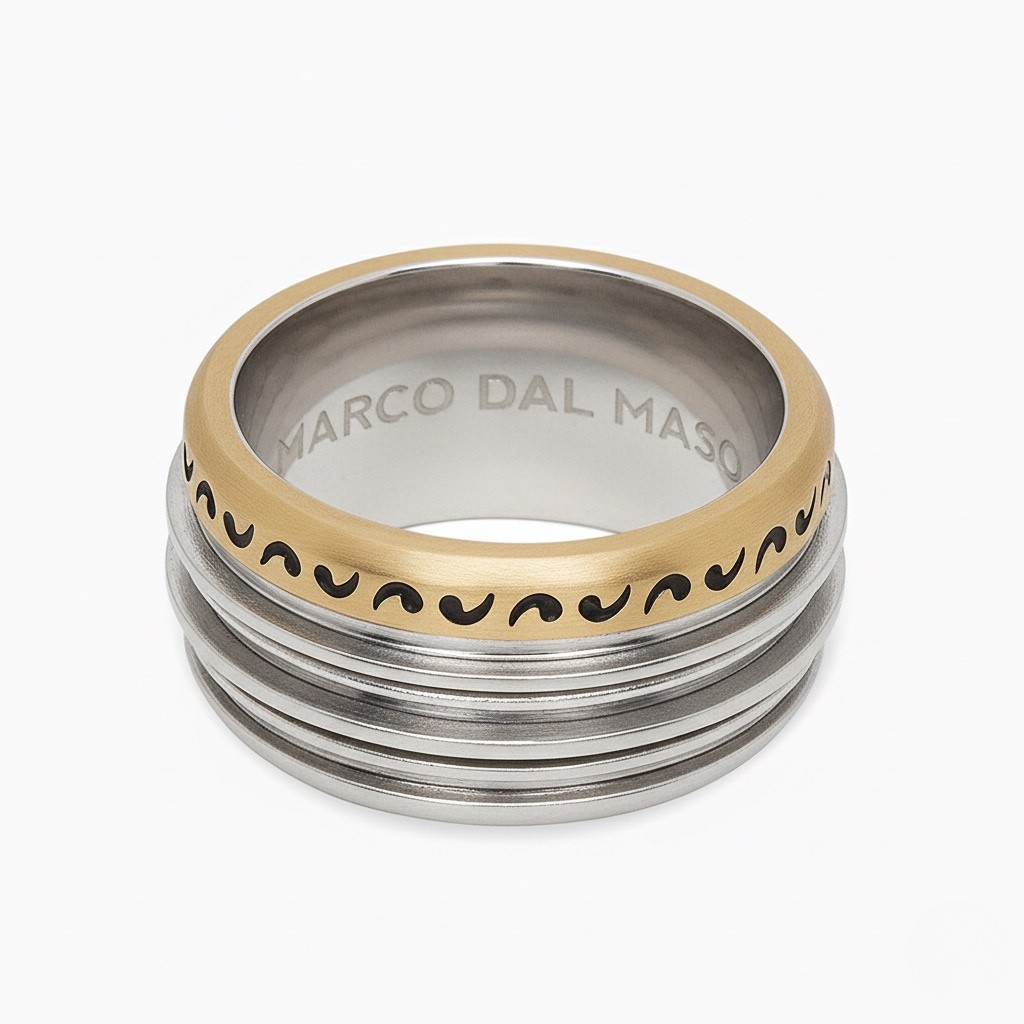 Stack of gold and silver rings with 'Marco Dal Maso' branding on a white background