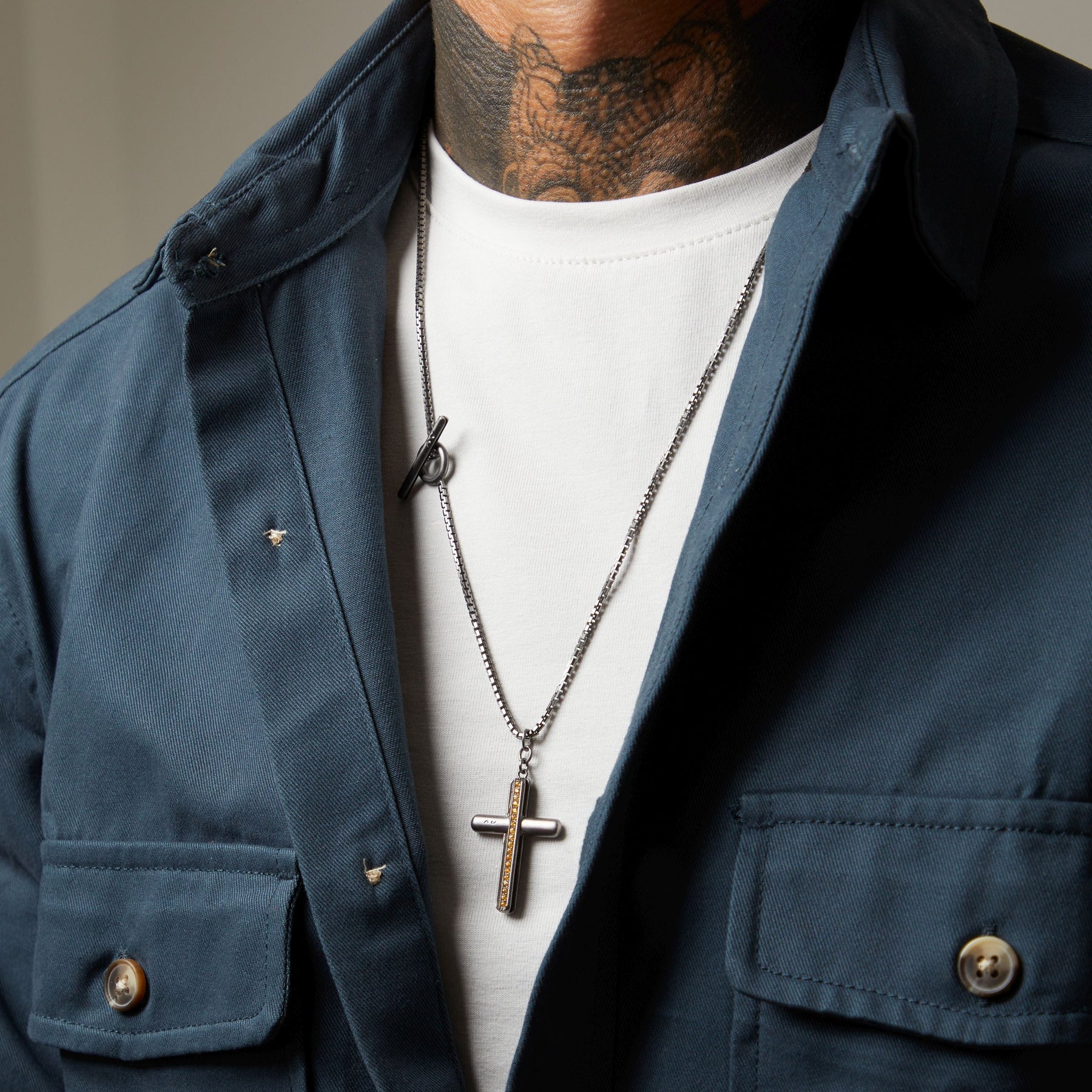 man with white shirt and denim wearing silver cross pendant with diamonds
