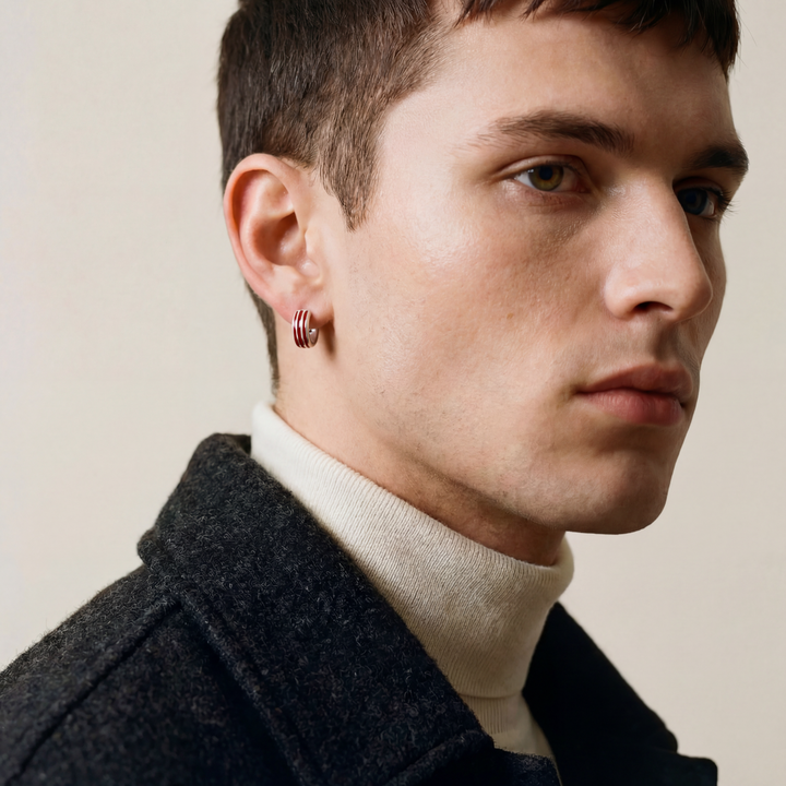 Man wearing a dark coat and light sweater with a neutral background