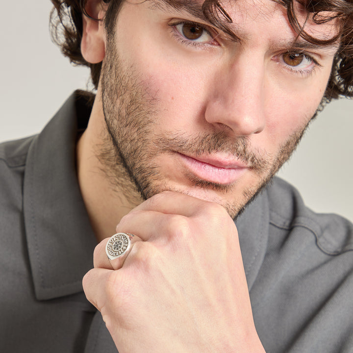 Man wearing a ring with a gray shirt on a neutral background