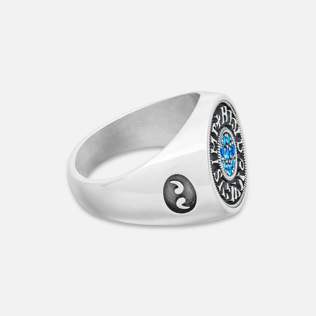 Silver ring with a blue gemstone and yin yang symbol on a white background