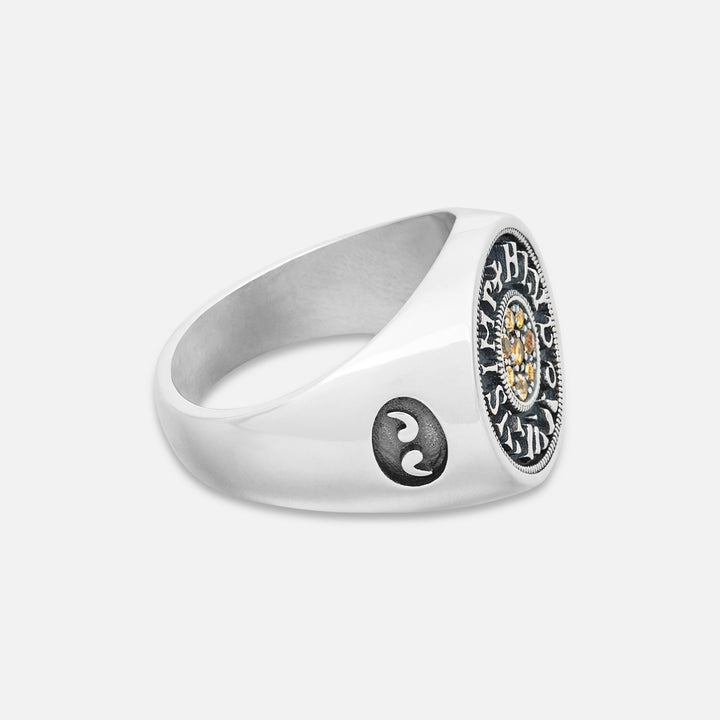 Silver ring with a yin yang symbol and intricate design on a white background