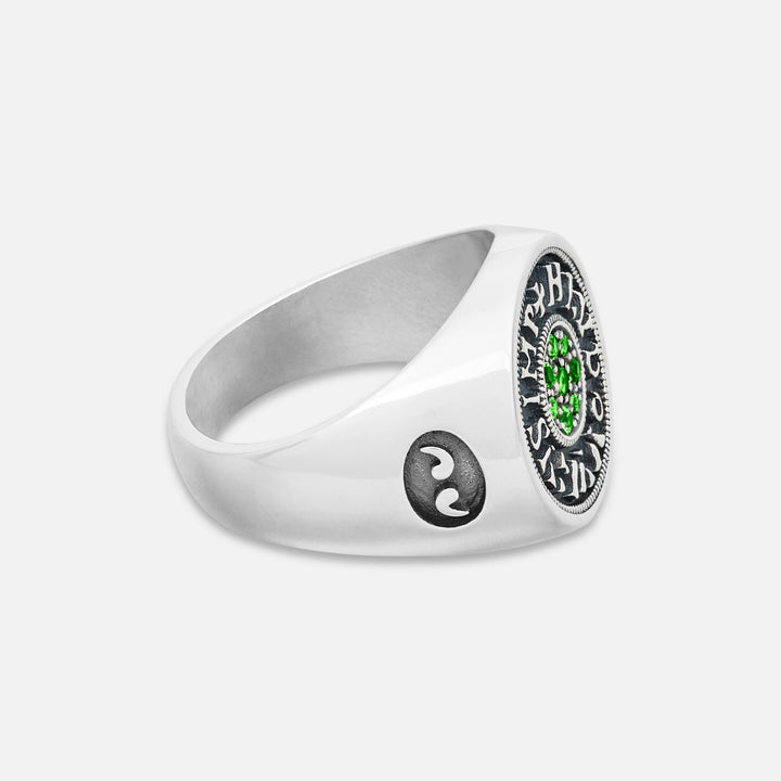 Silver ring with a yin yang symbol and green gemstone on a white background