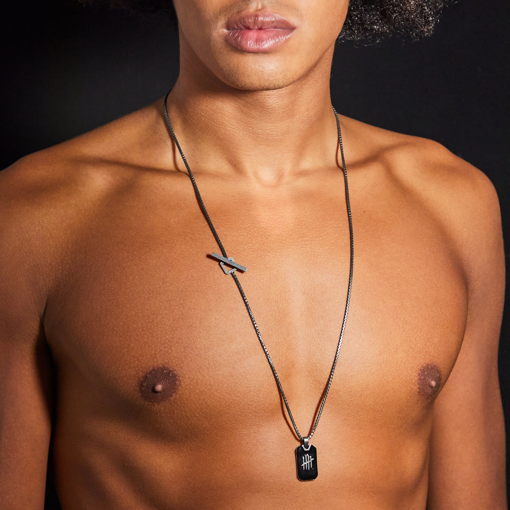Man wearing a necklace with a pendant on a black background