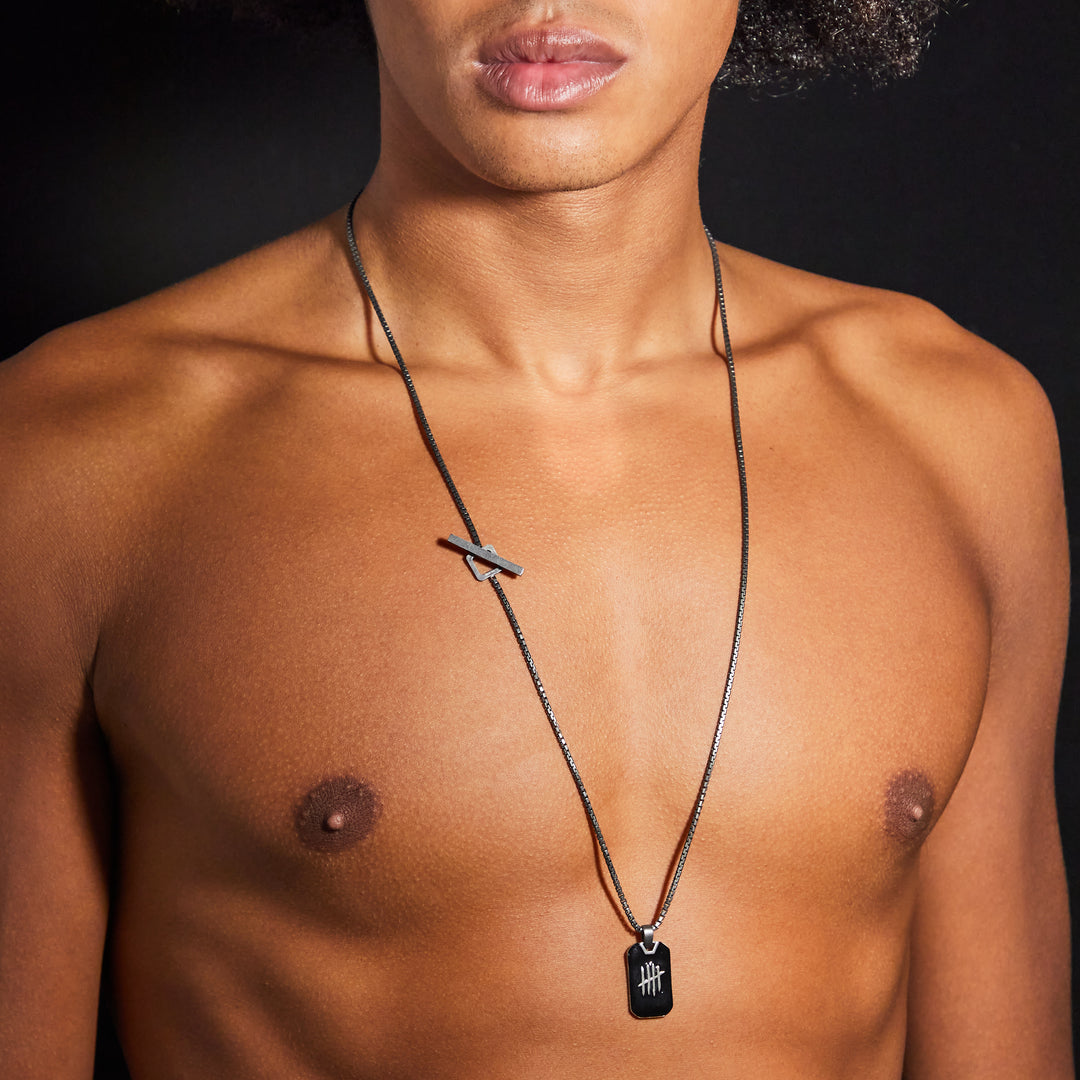 Man wearing a necklace with a pendant on a black background