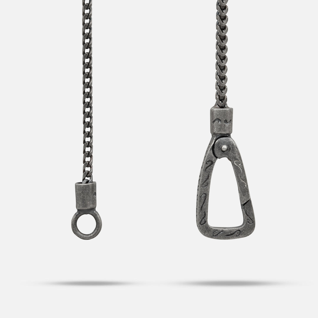 Metallic chain with a horse bit pendant on a white background