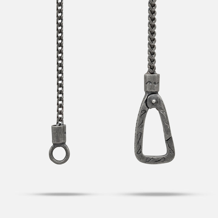 Metallic chain with a horse bit pendant on a white background