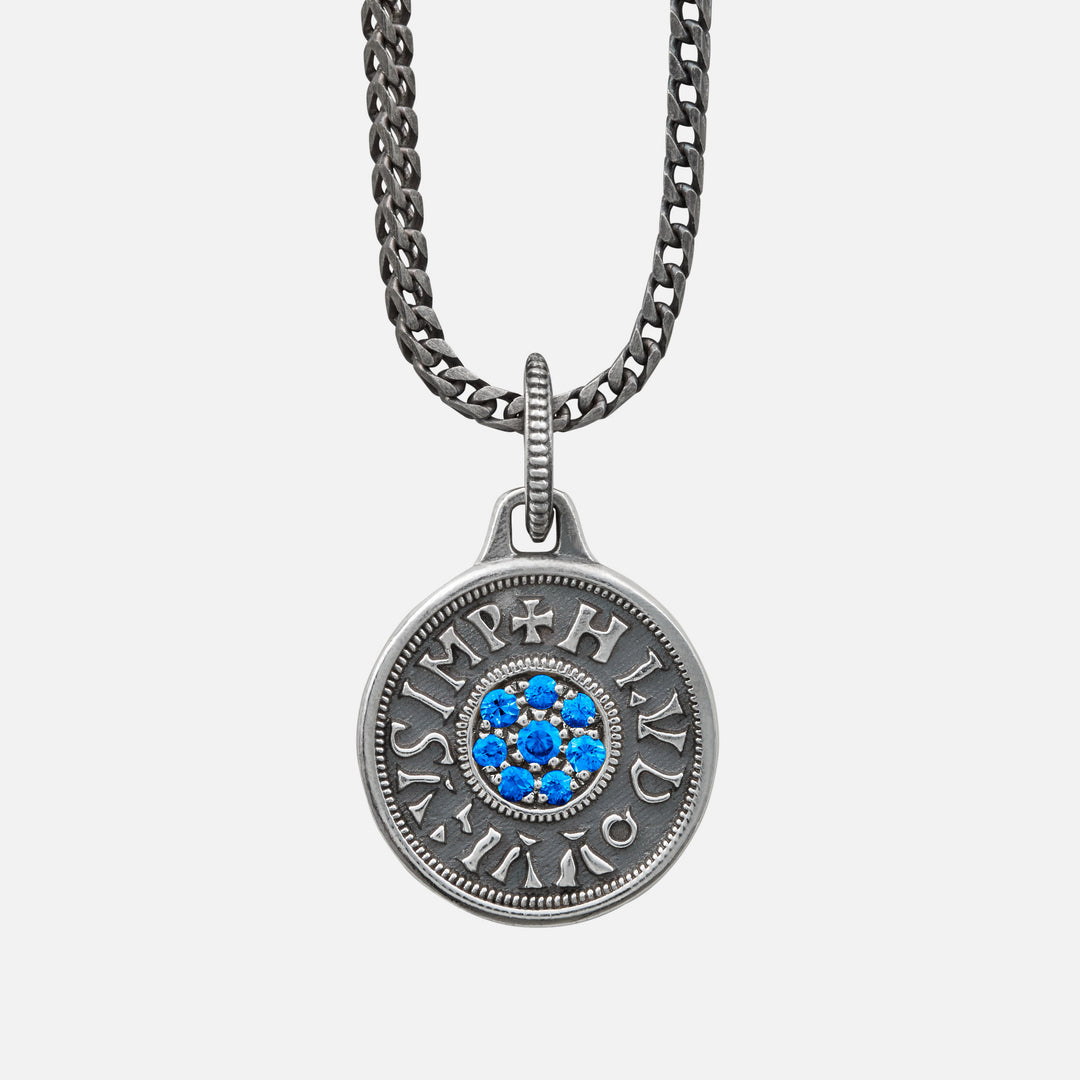 Silver necklace with a round pendant featuring blue stones on a light gray background