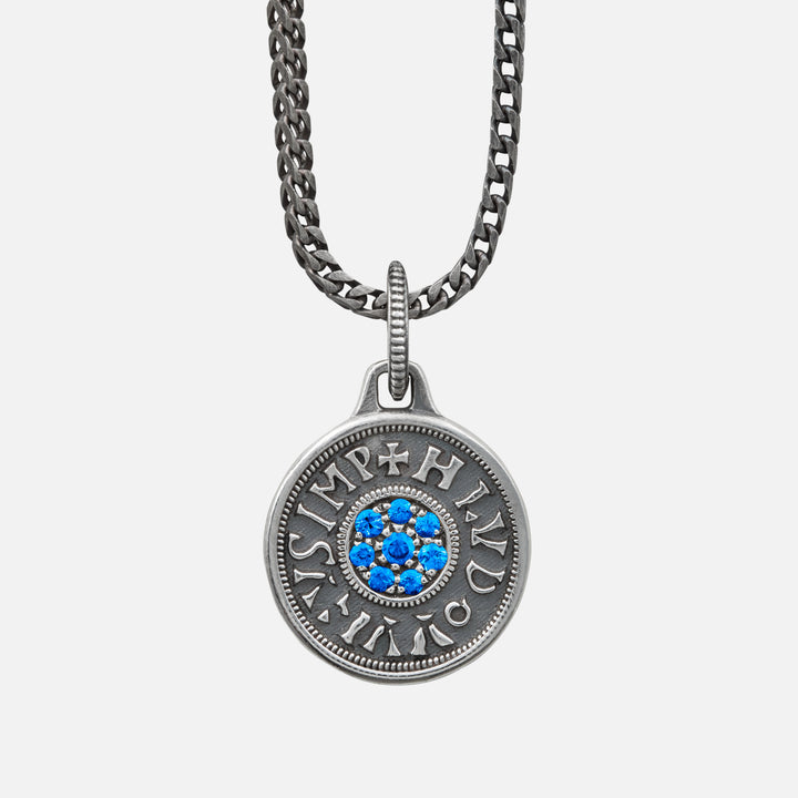 Silver necklace with a round pendant featuring blue stones on a light gray background