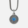 Silver necklace with a round pendant featuring blue stones on a light gray background