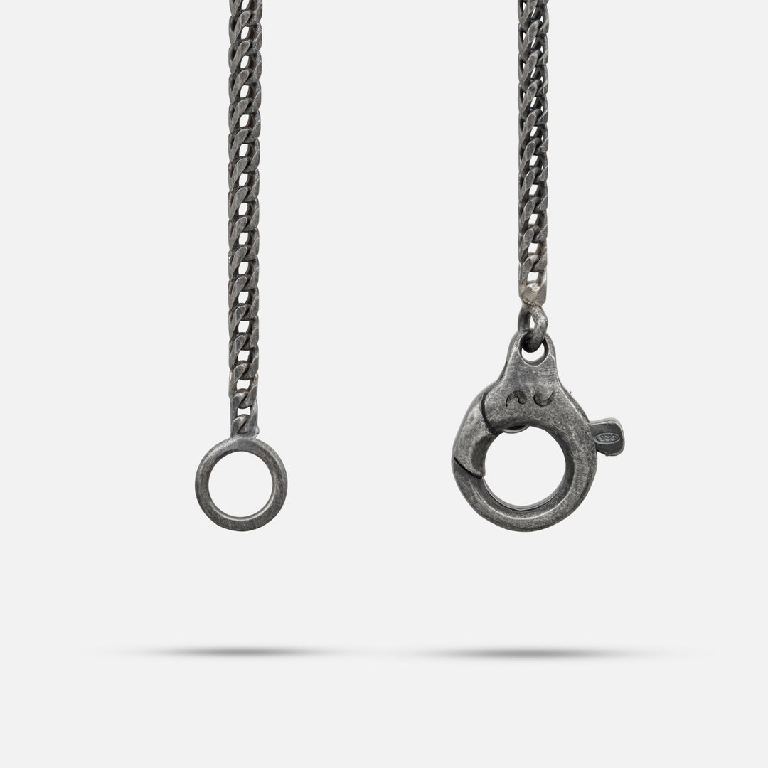 Close-up of a silver chain with clasp on a white background