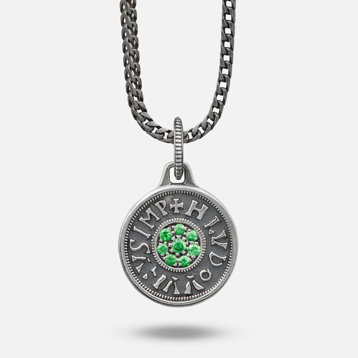 Silver pendant with green gemstones on a chain against a white background