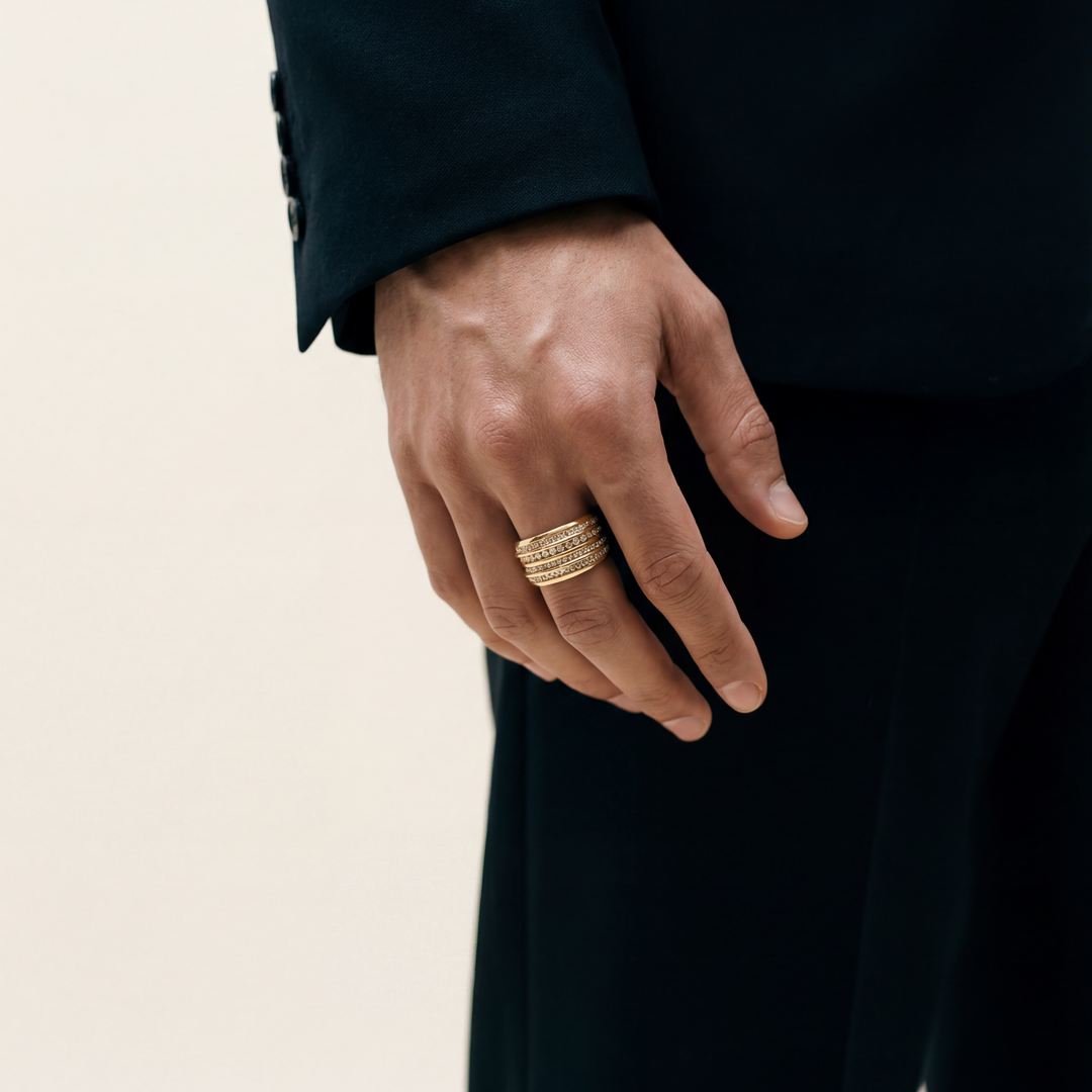 Hand wearing a gold ring with a plain background