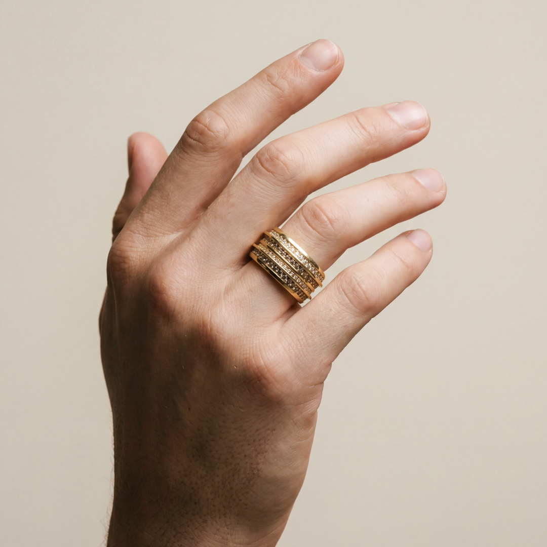 Hand wearing a gold ring on a beige background