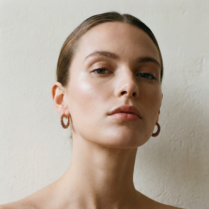 Close-up of a woman wearing earrings against a plain background