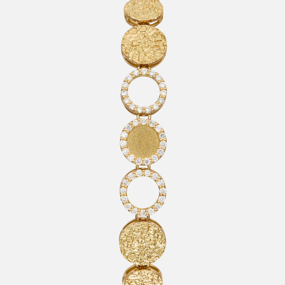 Close-up of the Frammenti Cascade Bracelet, featuring circular links in 18K yellow gold with alternating textured surfaces and white diamond accents.