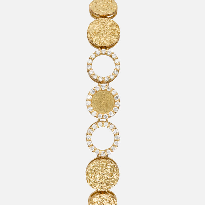 Close-up of the Frammenti Cascade Bracelet, featuring circular links in 18K yellow gold with alternating textured surfaces and white diamond accents.