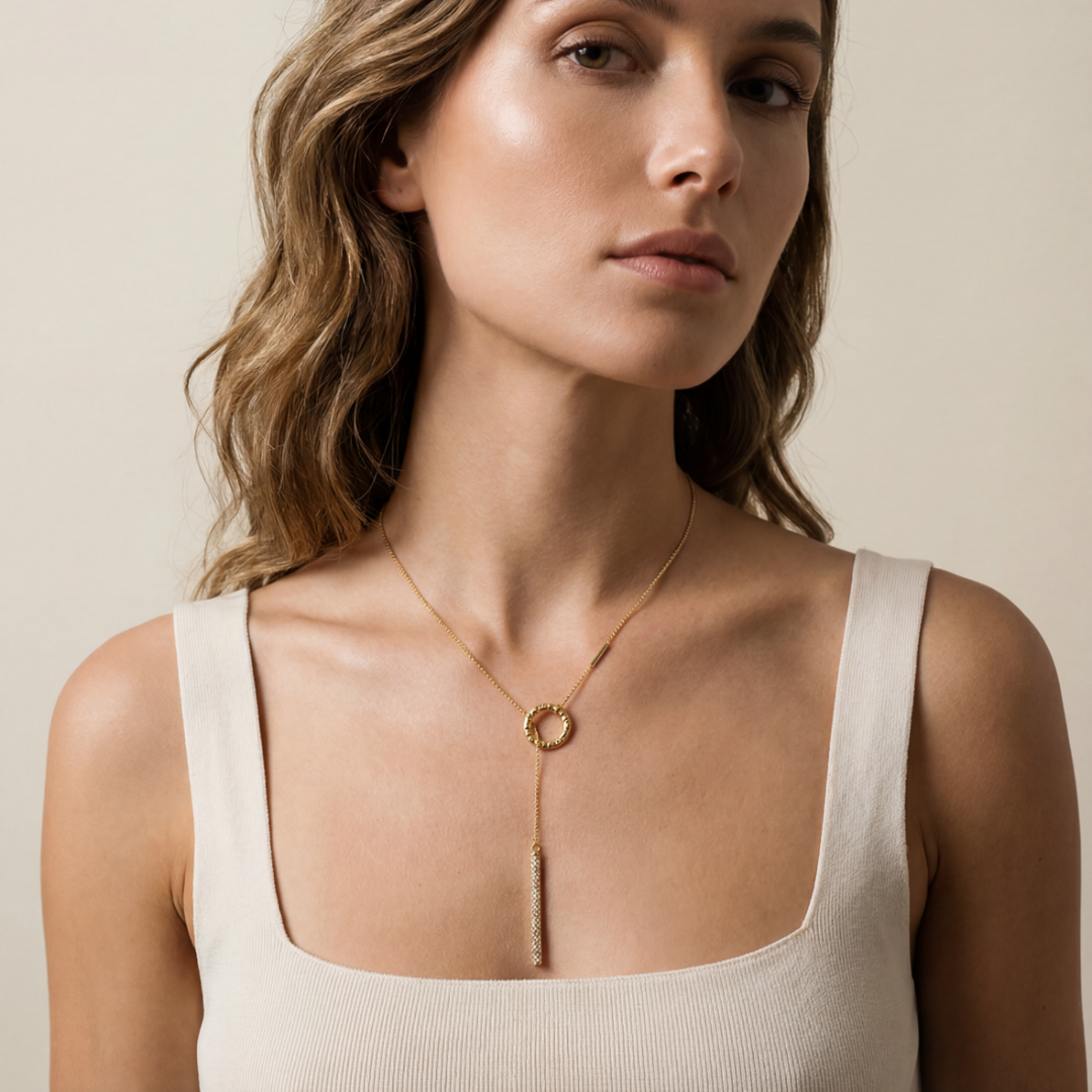 Woman wearing a gold necklace against a neutral background