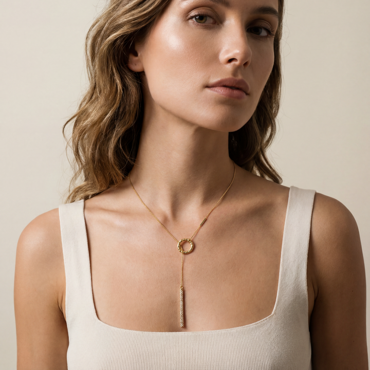 Woman wearing a gold necklace against a neutral background