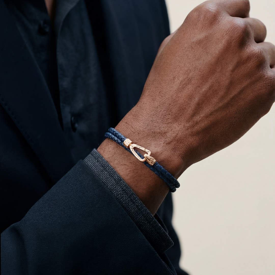 Person wearing a blue braided bracelet with a gold clasp on a neutral background