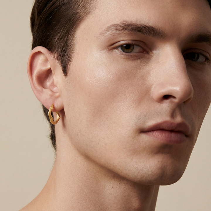 Close-up of a person wearing a gold hoop earring against a neutral background