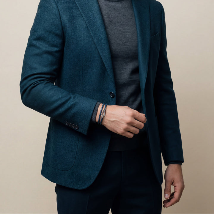 Man wearing a dark blue blazer over a gray turtleneck on a beige background