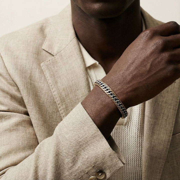 Man wearing a beige suit and silver bracelet on a neutral background
