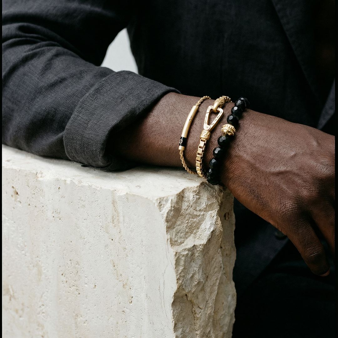 Person wearing multiple bracelets on a stone surface