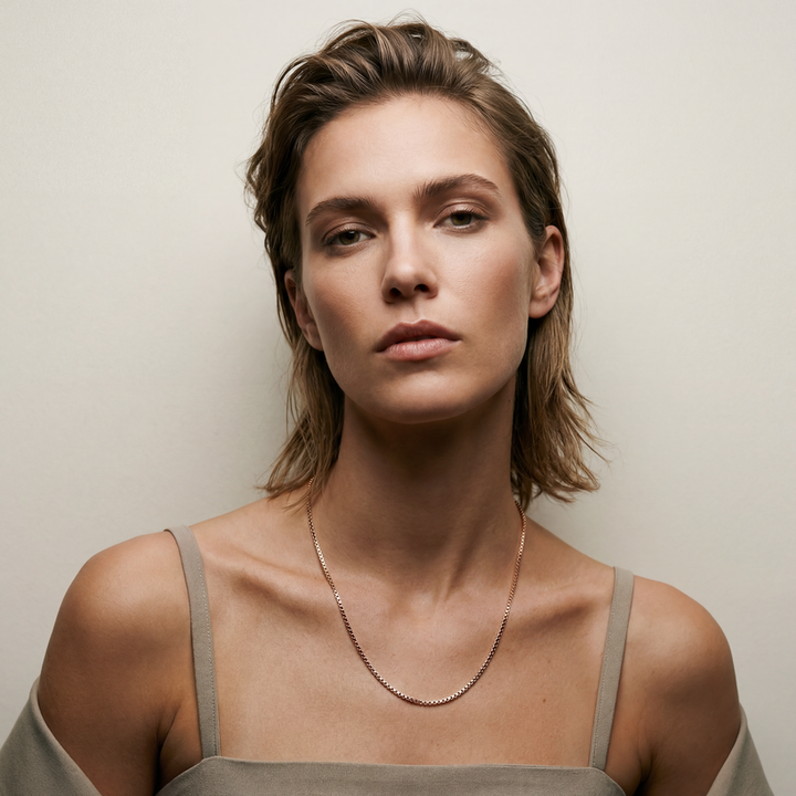 Woman wearing a delicate necklace against a neutral background