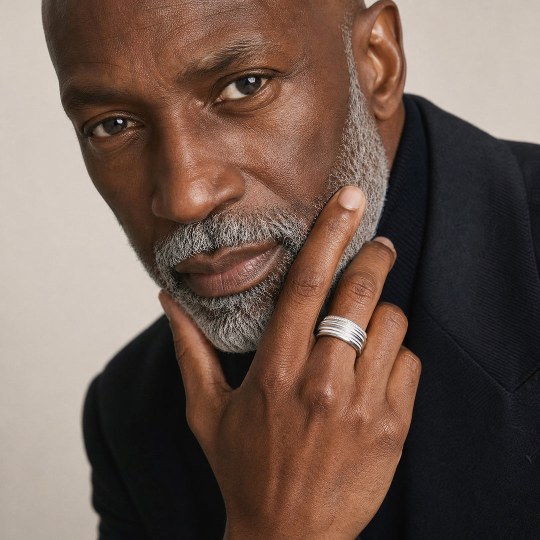 Close-up of a mature male model wearing the Acies Gemstone Band in polished silver with ivory enamel and white diamond detailing