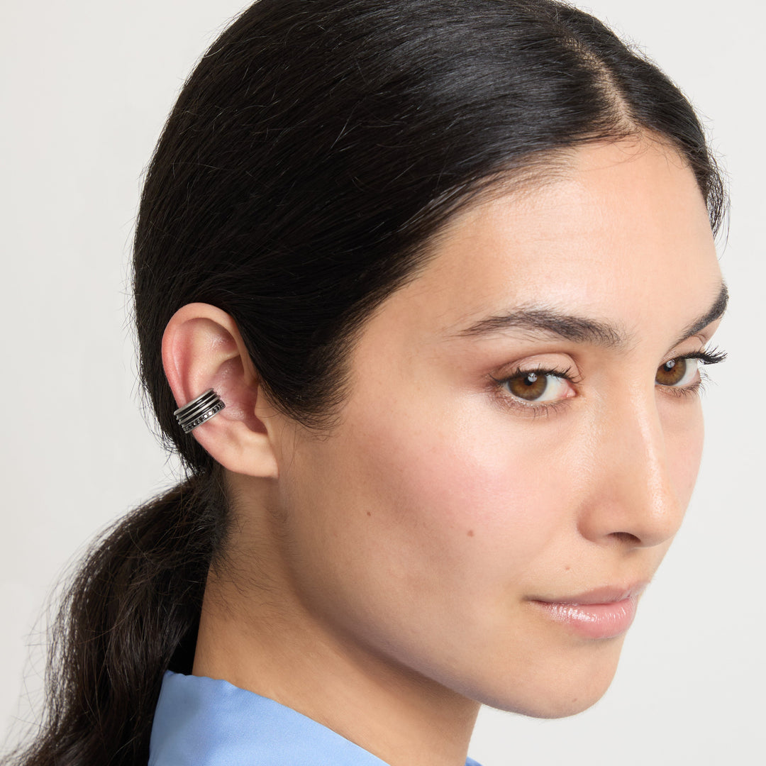 Angular portrait of dark silver ear cuff worn with a blue top.