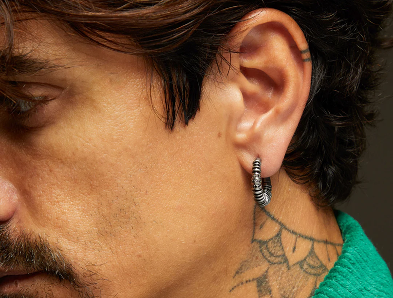 Man wearing a textured silver-tone hoop earring.