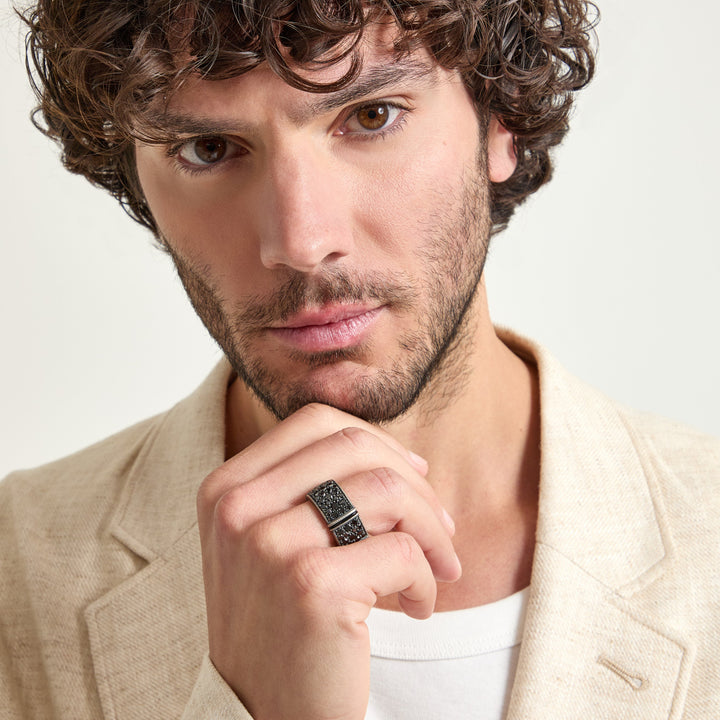 Facial portrait of statement ring displaying studded gems near lapel.