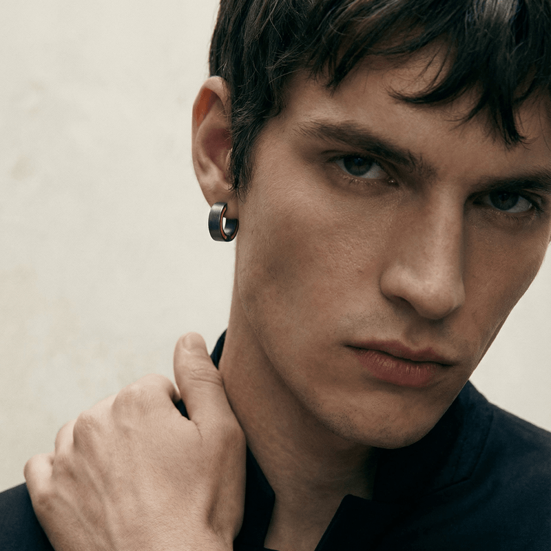 Male model wearing the MARCO DAL MASO Elan Silver Earring with yellow enamel detailing, shown in a close-up portrait highlighting the hoop design.