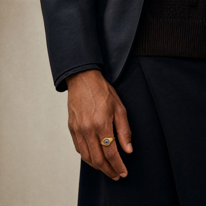 Model wearing the MARCO DAL MASO Icon Blue Sapphire Signet Ring, featuring a polished gold-tone finish and a central blue sapphire.