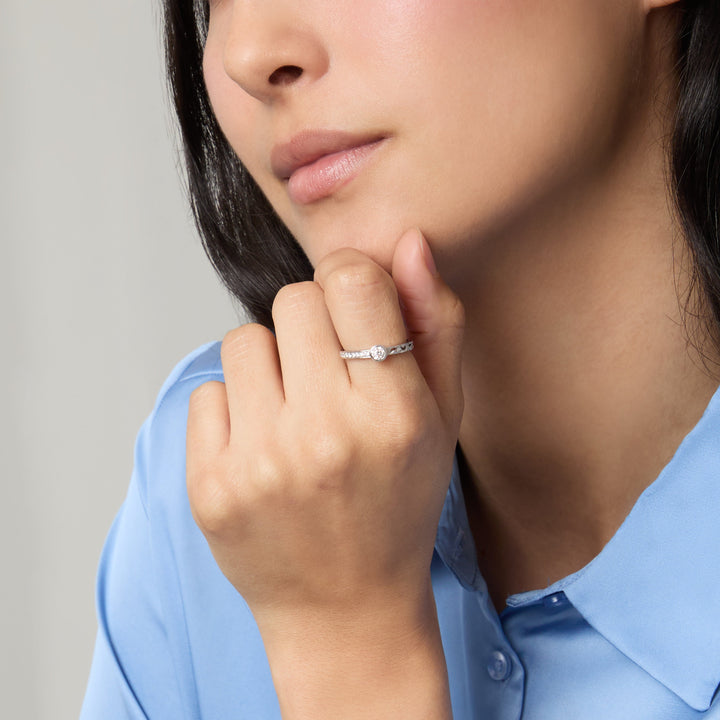 Female model wearing the MARCO DAL MASO Orion Gemstone Ring in white gold with white diamonds, featuring a central round diamond and delicate diamond-set band, shown in a close-up portrait.