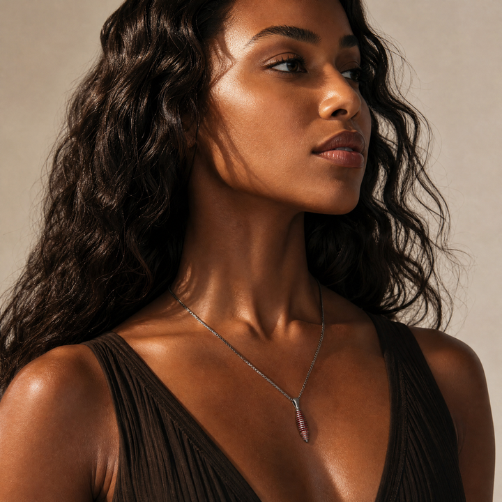 Model wearing the Acies Cocoon Gemstone Pendant in oxidized silver with red enamel and red sapphires.