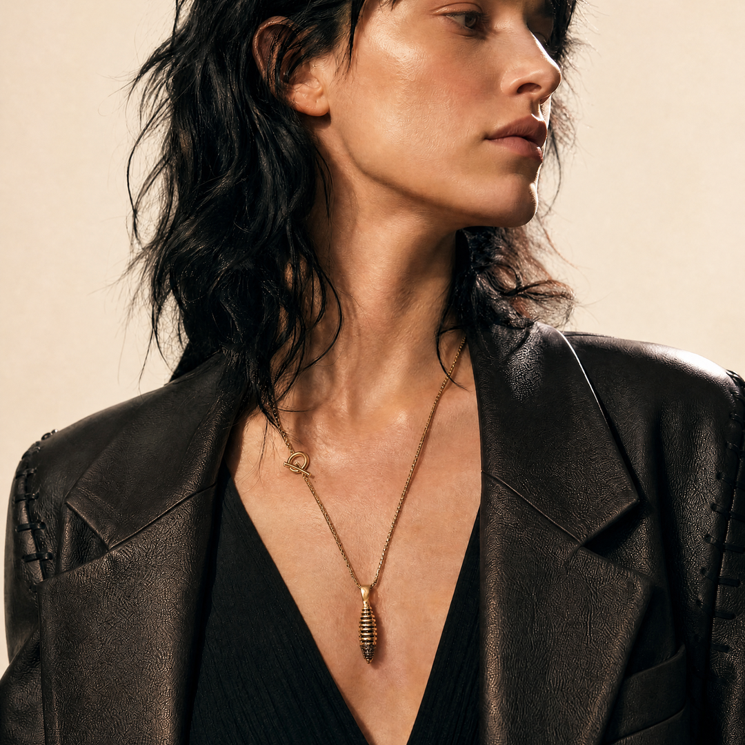 Model wearing the Acies Cocoon Gemstone Pendant in yellow gold matte vermeil with black enamel and black diamonds.