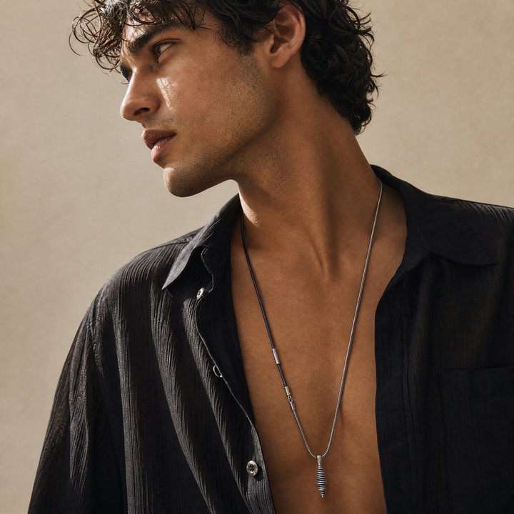 Model wearing the Acies Cocoon Pendant in oxidized silver with blue enamel and blue leather.