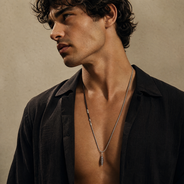 Model wearing the Acies Cocoon Pendant in oxidized silver with brown enamel and brown leather.